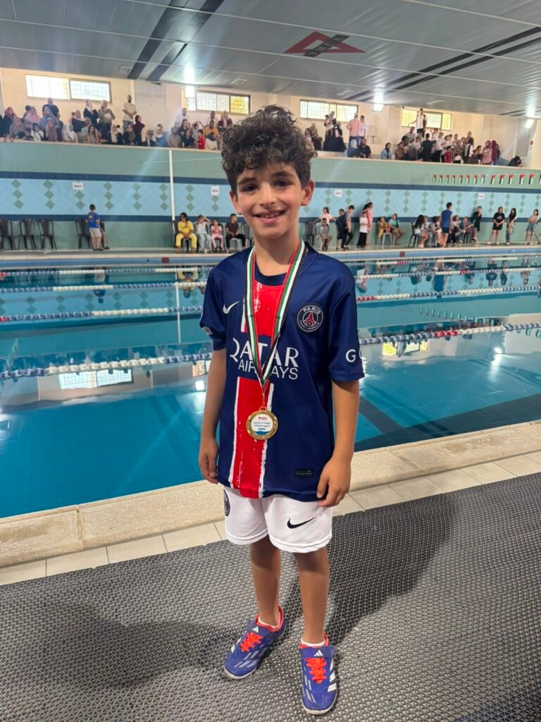 Young De La Salle swimmer wearing a gold medal beside the swimming pool.