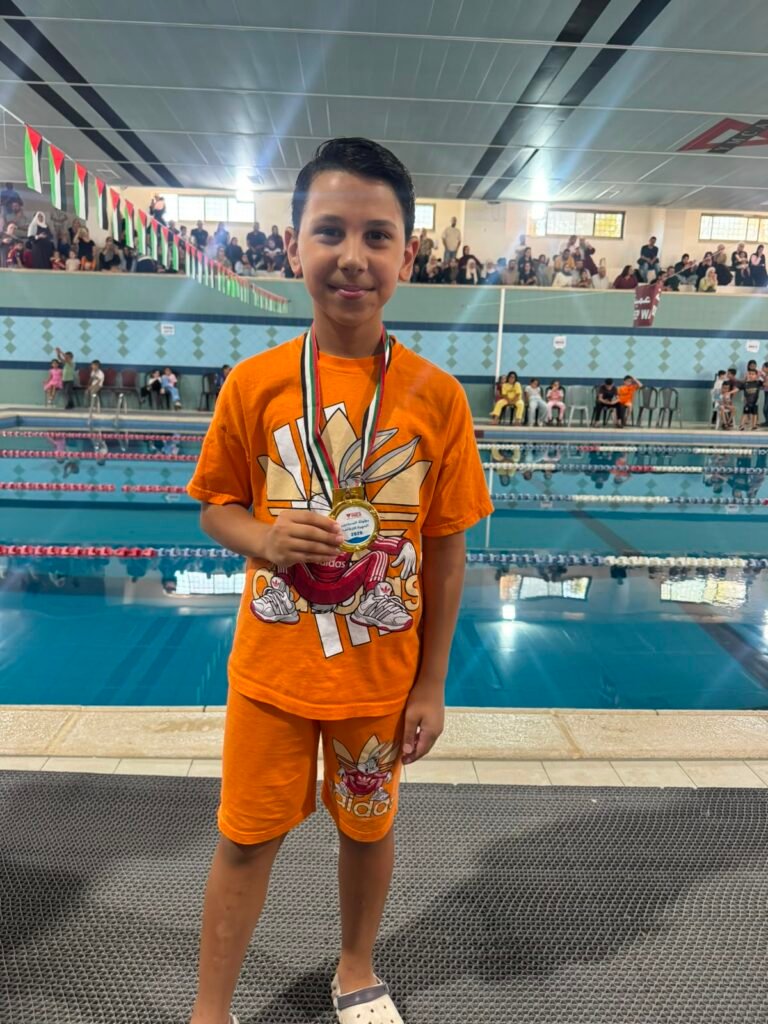 Young De La Salle swimmer proudly holding a gold medal.