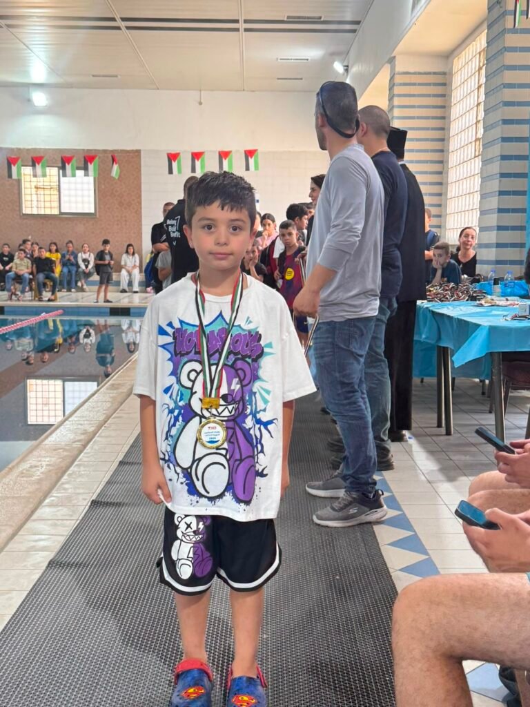 Young swimmer wearing a medal at the poolside awards area.